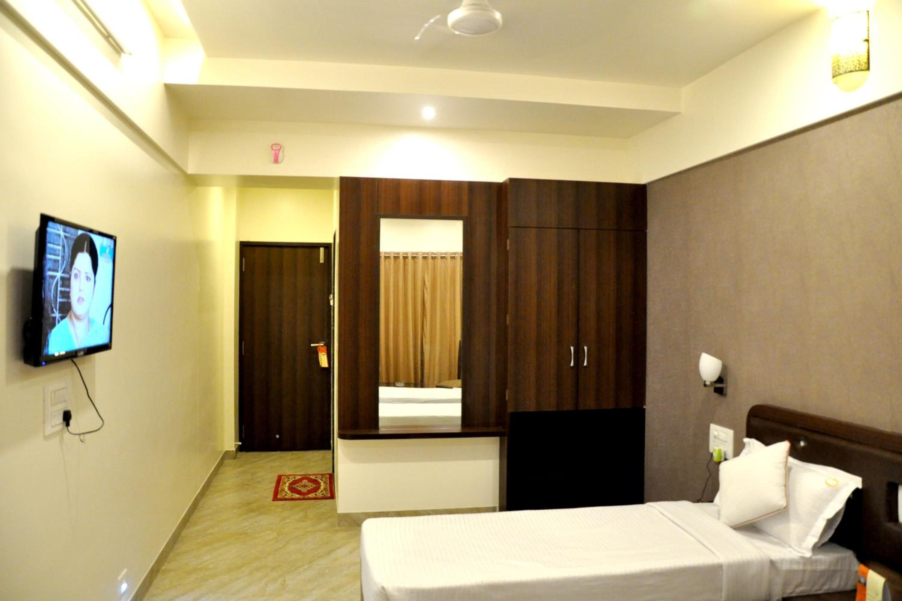 A hotel room with a bed, a TV, a wardrobe, and a mirror.