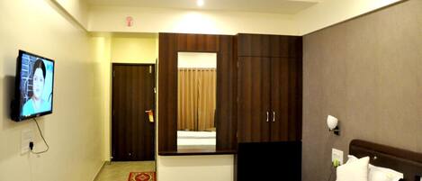 A hotel room with a bed, a TV, a wardrobe, and a mirror.