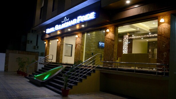 A hotel entrance with a staircase, a neon sign, and a reception area. - Hotel Gulmohar Pride (Ahmednagar)