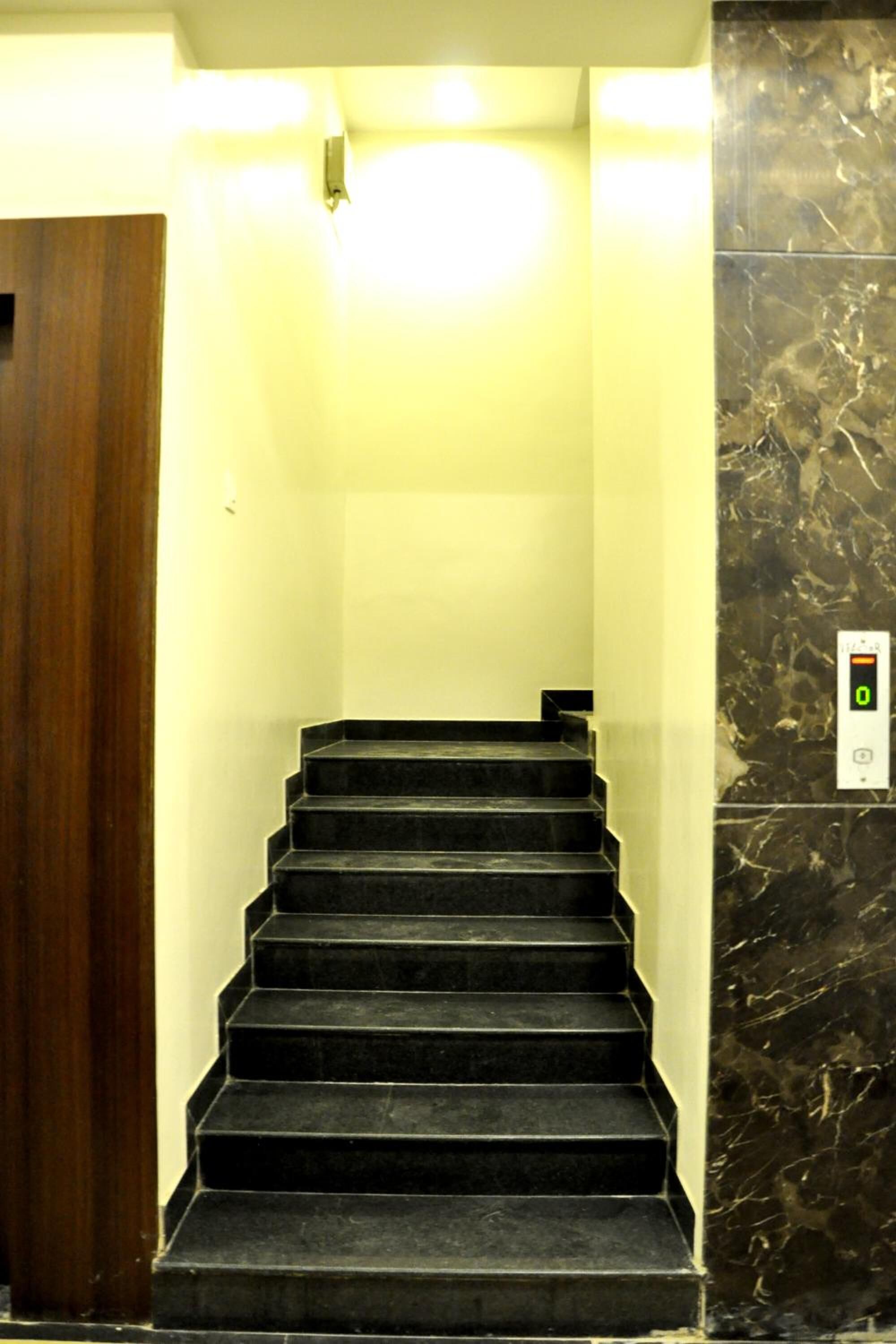 Una escalera con un panel de control digital para ascensor en la pared.