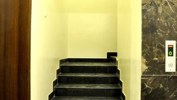 Una escalera con un panel de control digital para ascensor en la pared.