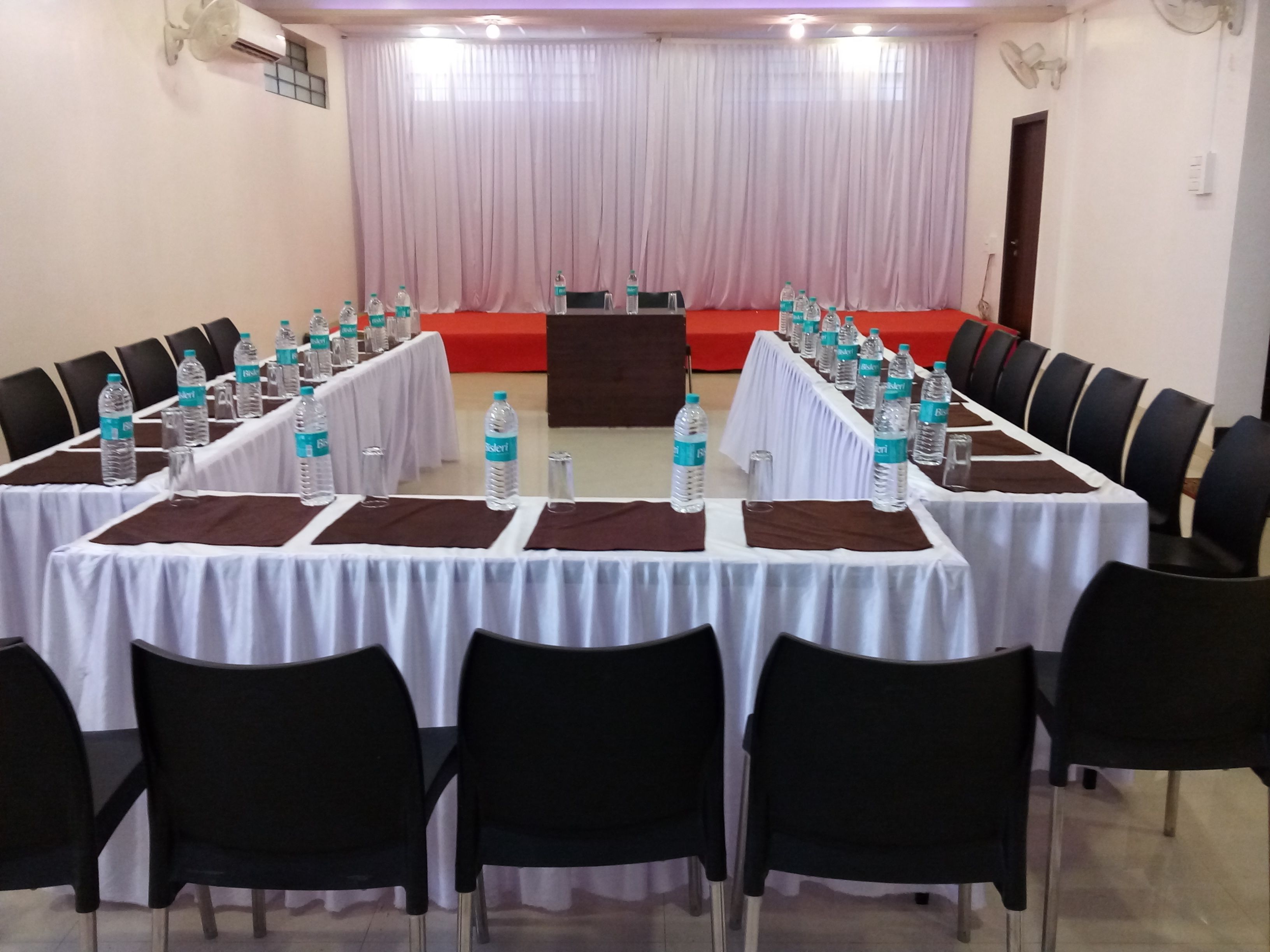 A conference room with tables set for meetings, equipped with water bottles and nameplates.