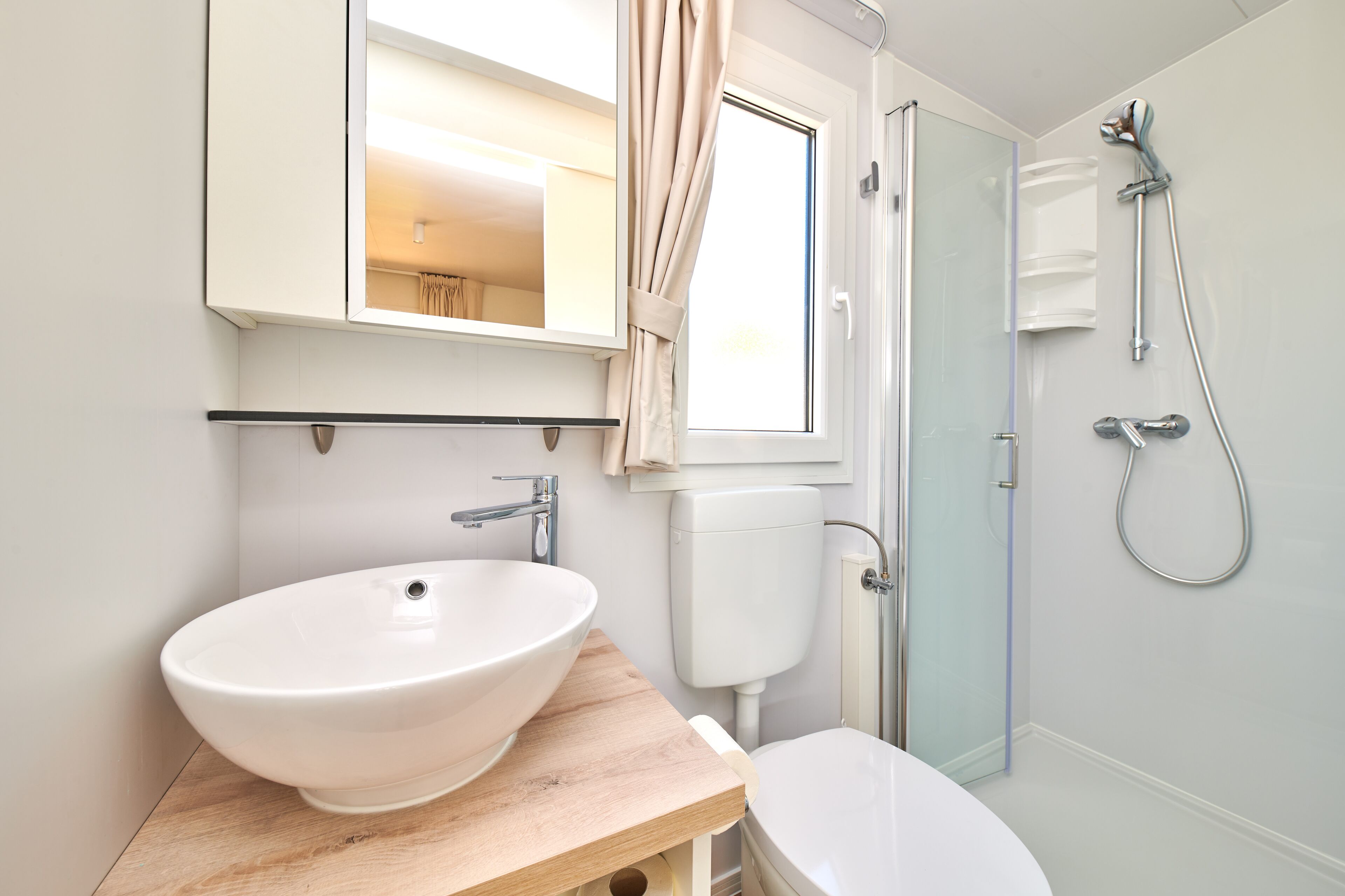 Une salle de bain avec un lavabo blanc, des toilettes et une douche à parois de verre.