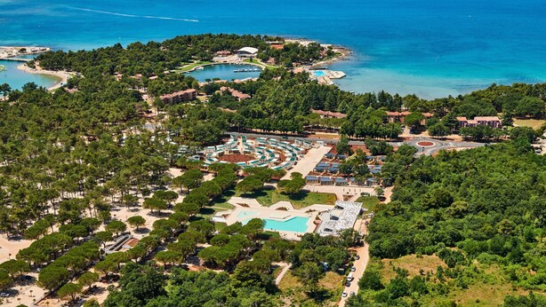 An aerial view of a coastal resort with multiple swimming pools, a central courtyard, and surrounding greenery. - Mobile Homes Stella Maris (Umag)