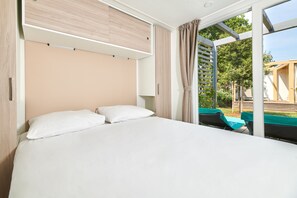 A modern hotel room with a large bed, a sliding door to a balcony, and a view of the outdoors. - Mobile Homes Stella Maris (Umag)
