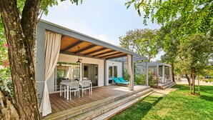 A modern outdoor patio with a wooden deck, a dining area, and a covered seating area. - Mobile Homes Stella Maris (Umag)