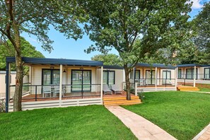 A row of modern, single-story buildings with large windows and a covered outdoor area with seating. - Mobile Homes Stella Maris (Umag)