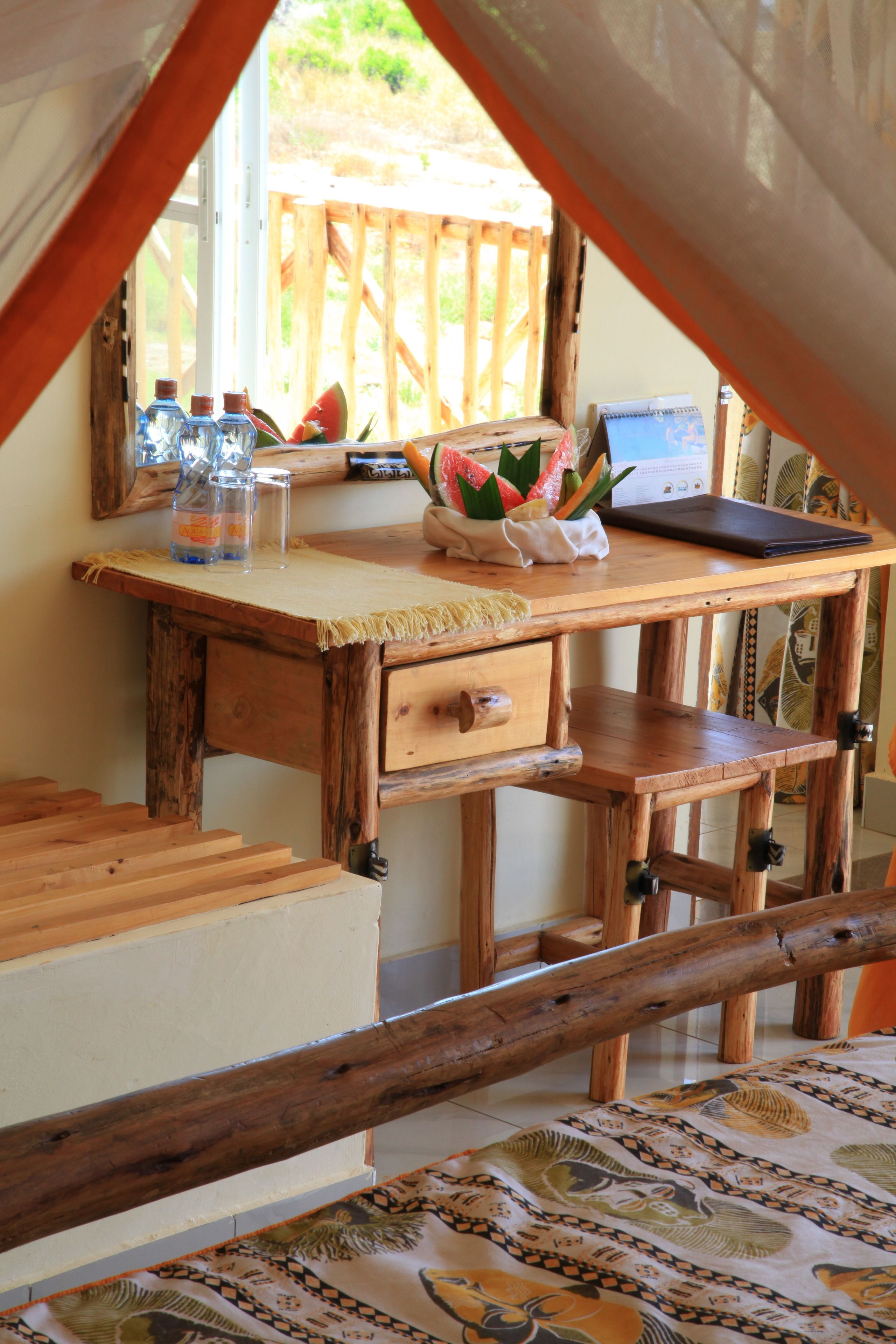 Un escritorio de madera con una computadora portátil, cuadernos y un frutero.