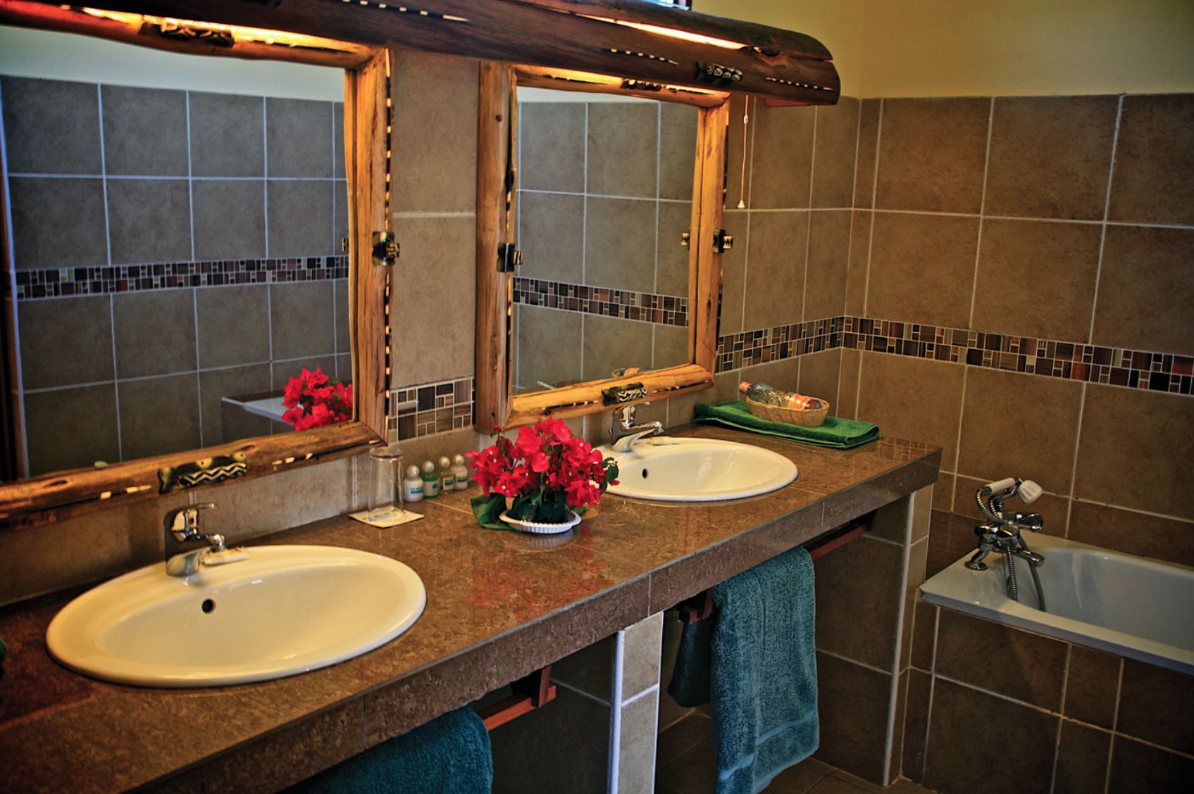 A bathroom with two sinks, a mirror, a bathtub, and a tiled wall.