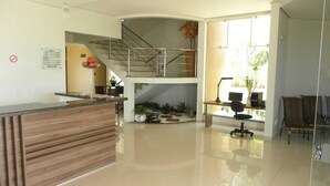 A modern hotel lobby with a reception desk, a staircase, seating area, and a small indoor garden. - Executive Hotel (Lucas do Rio Verde)