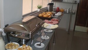 A buffet setup with various food items and a self-service beverage station. - Executive Hotel (Lucas do Rio Verde)