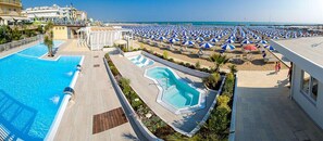 Un resort con piscina, ombrelloni da spiaggia e vista sull'oceano.