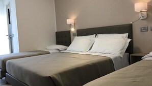 Une chambre d’hôtel avec deux lits, une tête de lit, des lampes de chevet et une porte.