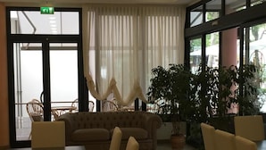 Un hall d’entrée avec un canapé, des fauteuils, une table et une grande plante en pot.