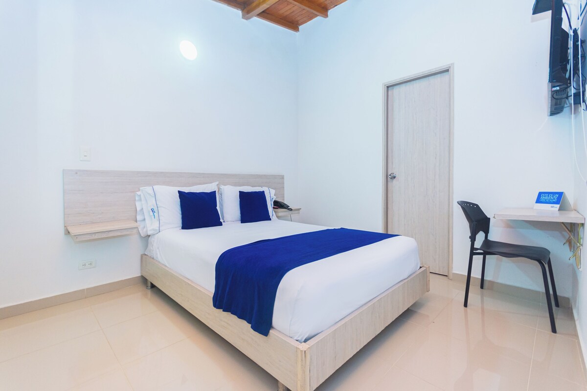 A neatly arranged bedroom with a bed, bedside table, chair, and a door.