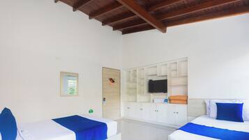 A hotel room with two beds, a TV, and a white wardrobe.