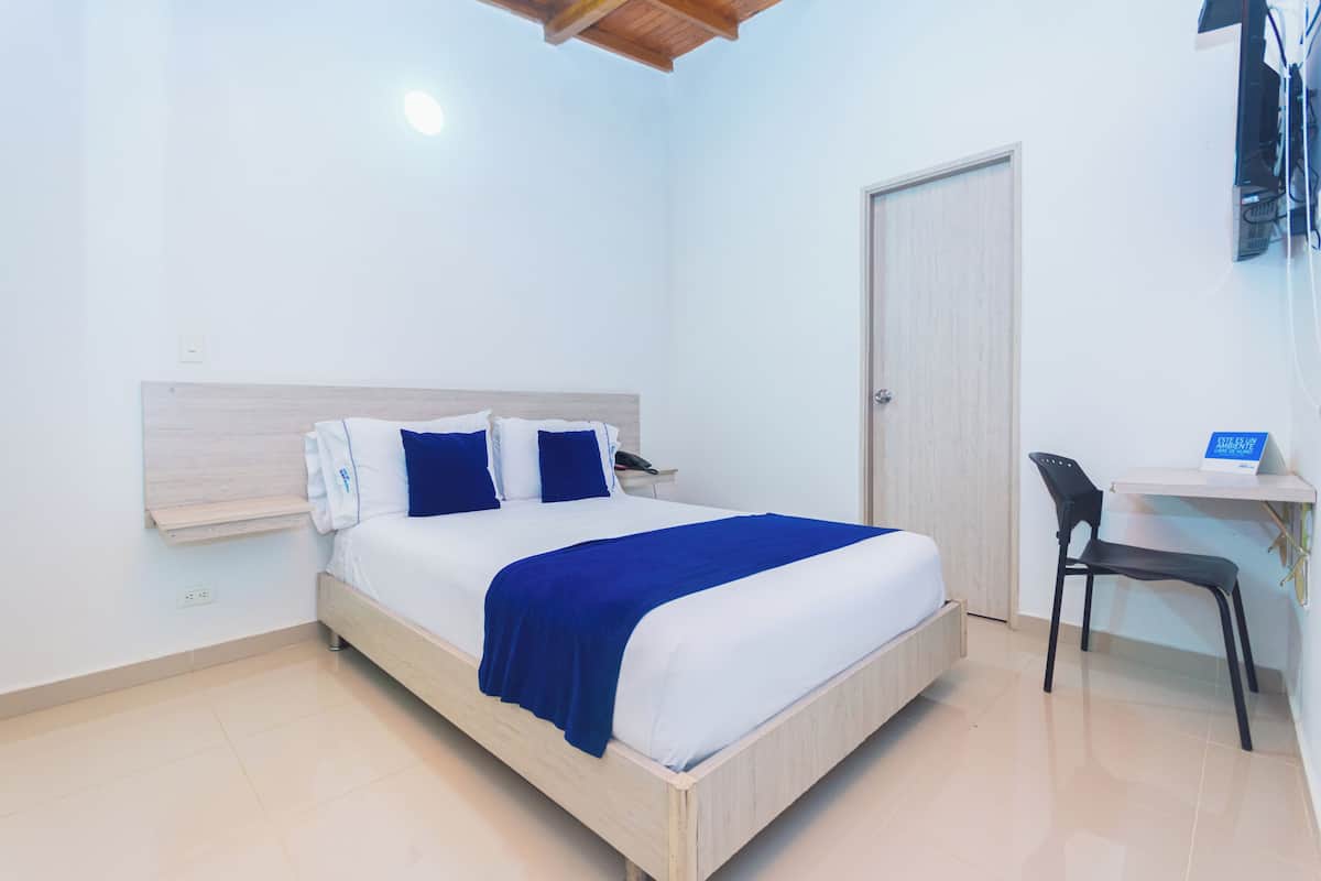 Een slaapkamer met een bed, een bureau en een stoel.