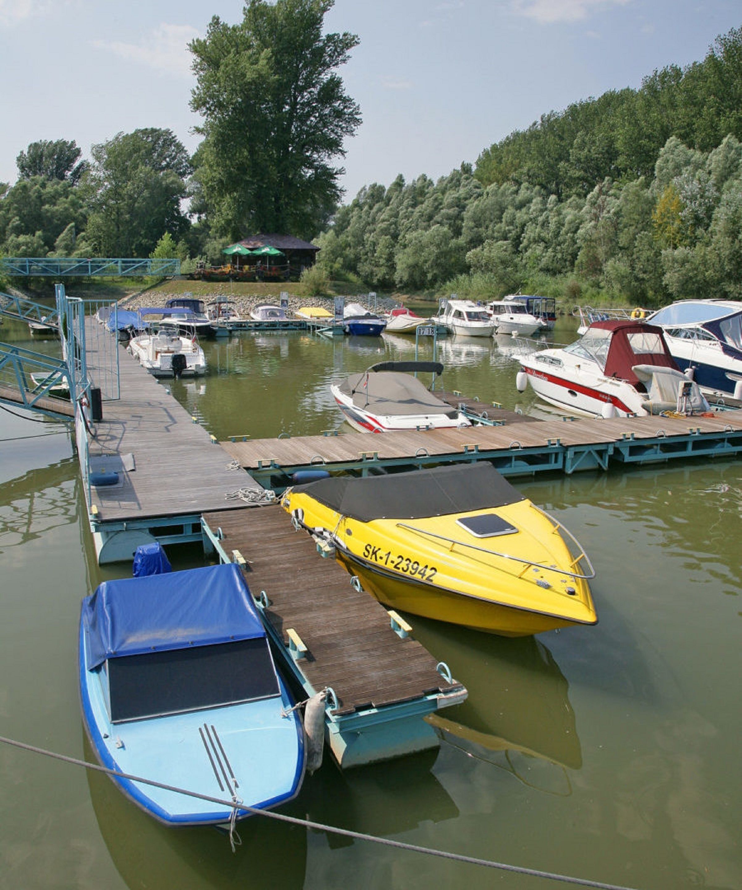 A dock with several boats, including a yellow one with the number SK-1-23942, and a blue one.