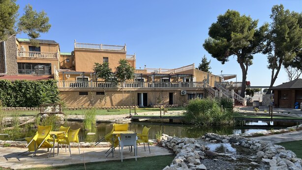 A courtyard with a pond, yellow chairs, and a building with balconies. - Hotel El Cisne (Zaragoza)