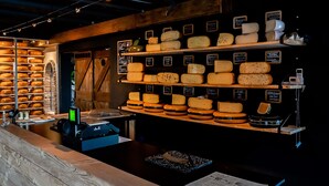 A cheese display with various types of cheese on shelves. - Ruyge Weyde Logies (Oudewater)