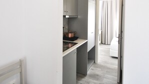 A narrow hallway leading to a bedroom with a bed and a bathroom. - Imeres Studios & Apartments (Kassandra)