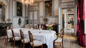 A formal dining room with a large table set for six, surrounded by wooden chairs.