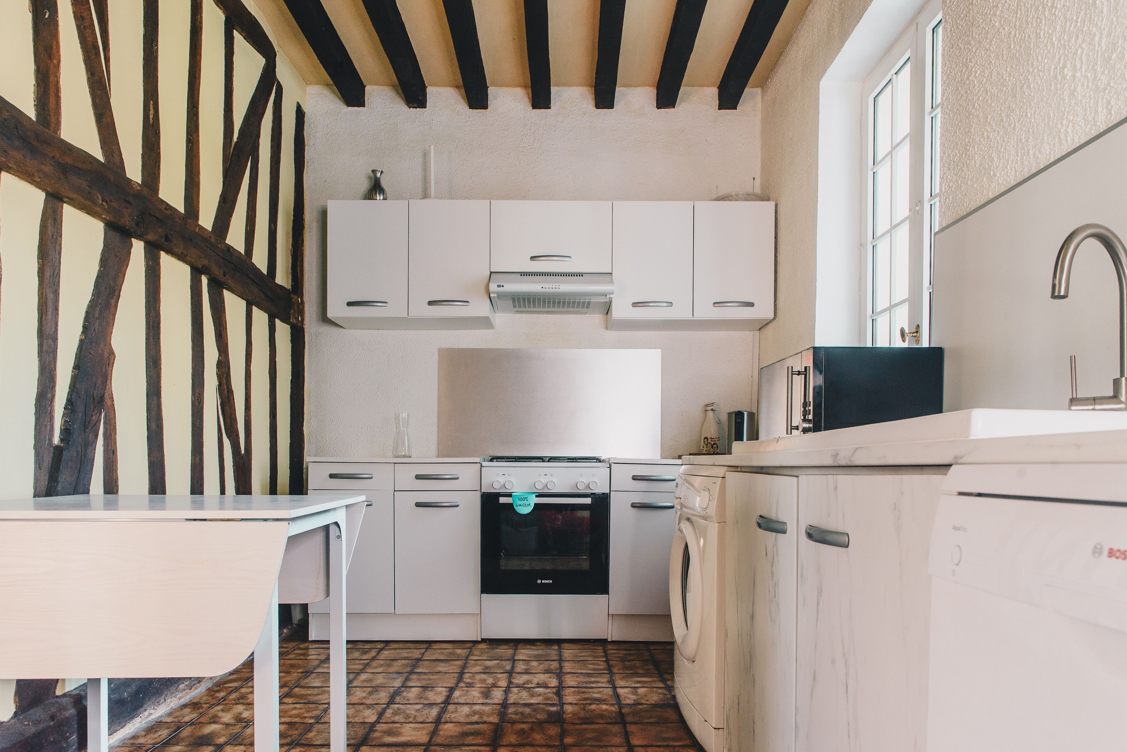 A kitchen with white cabinets, a Bosch oven, and a washing machine.