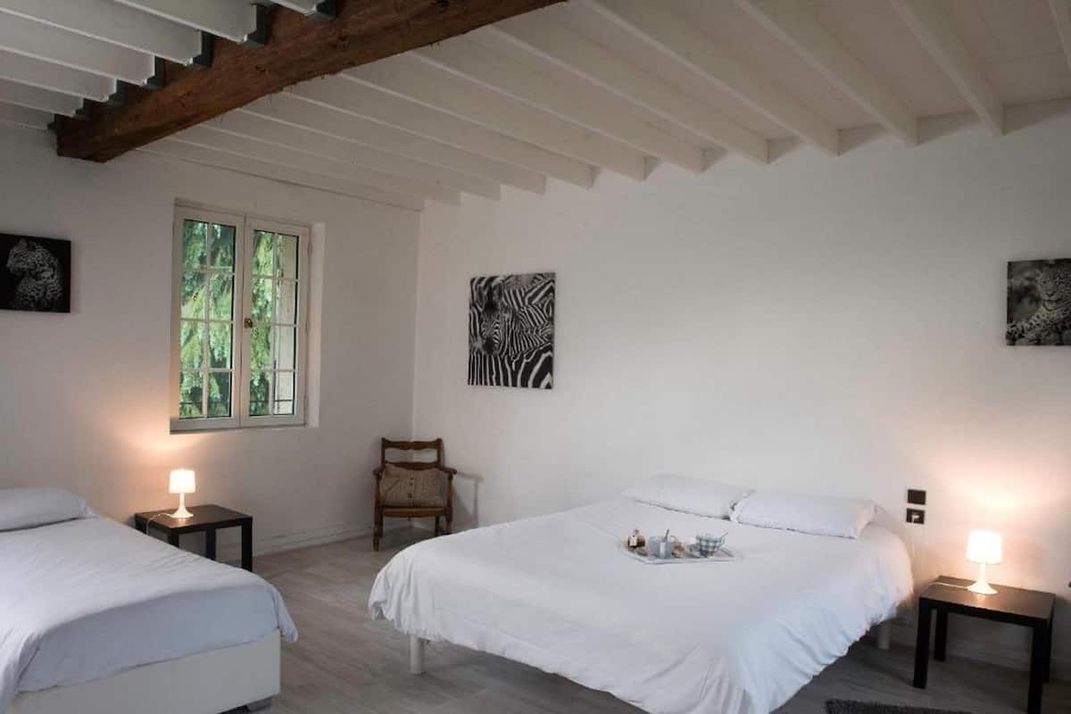 A bedroom with two beds, a window, and artwork on the walls.