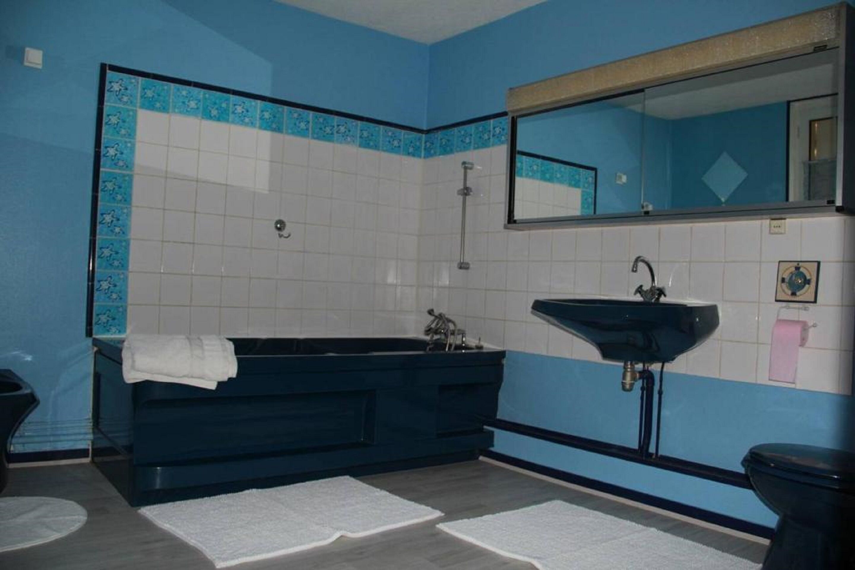 A bathroom with a dark bathtub, a sink, and a toilet.