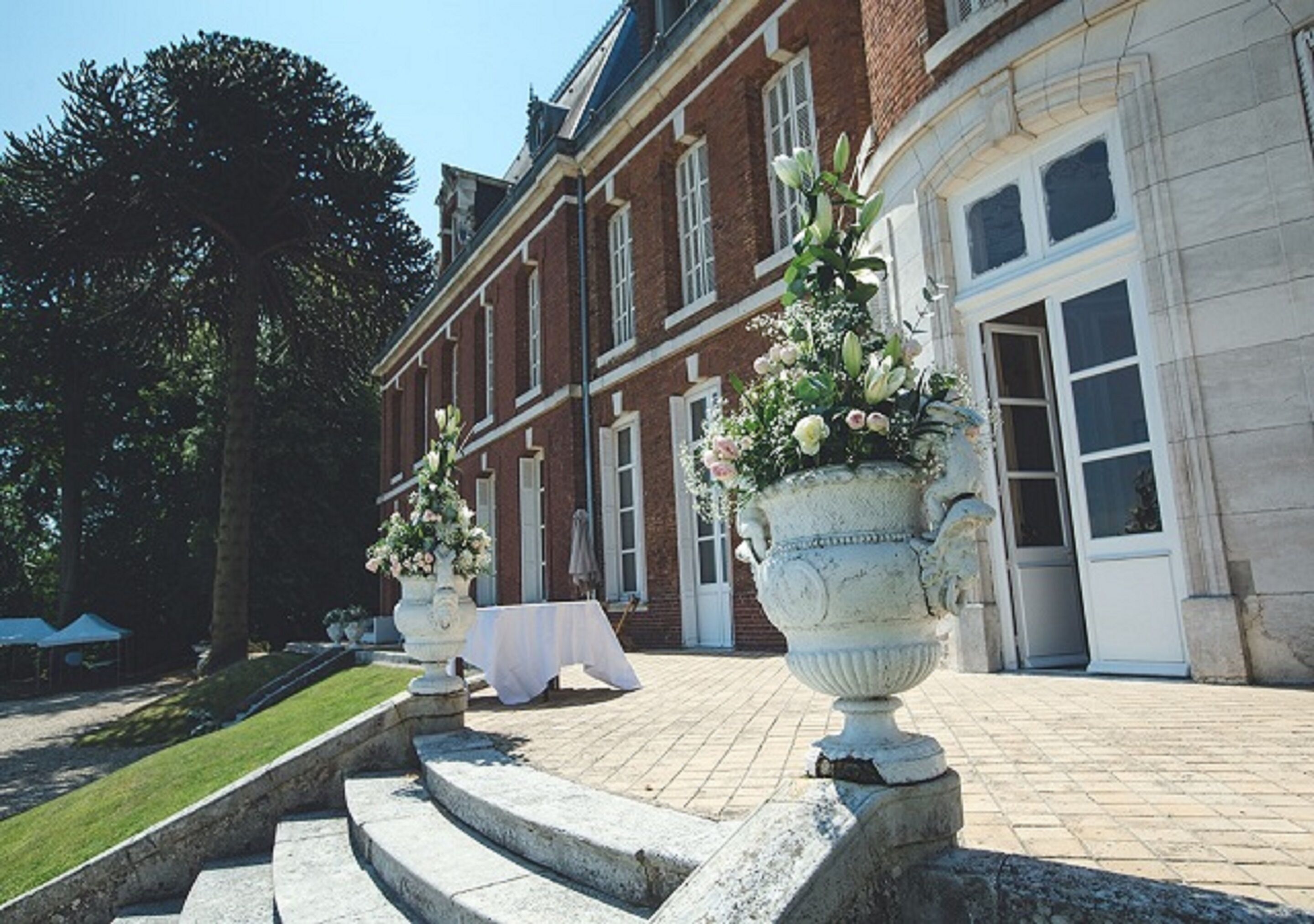 A grand building with a brick facade, large windows, and a well-maintained lawn.