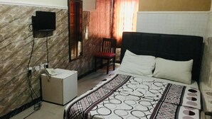 A hotel room with a bed, a chair, a desk, a telephone, and a TV mounted on the wall. - Lekki Central Hotel (Lekki)