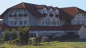 Un hotel de estilo arquitectónico europeo tradicional, con fachada simétrica, múltiples ventanas y tejado de tejas rojas.