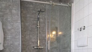 Un baño moderno con ducha de vidrio, inodoro blanco y piso de madera.
