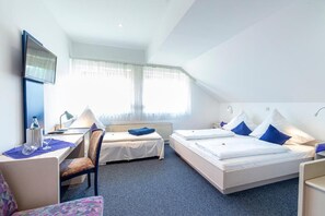 A hotel room with two beds, a desk, a chair, a TV, and a window with curtains.