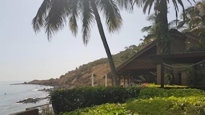 Une vue sur la côte, avec une plage, des palmiers et un bâtiment doté d’un patio couvert.