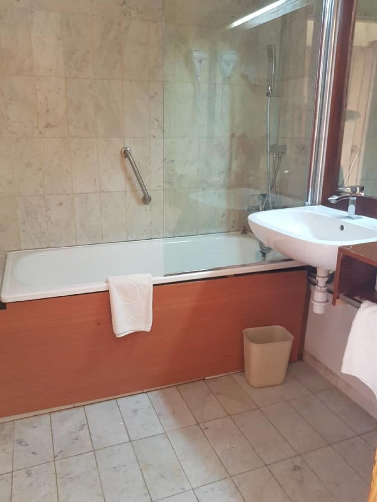 A bathroom with a bathtub, a sink, a mirror, and a glass shower enclosure.