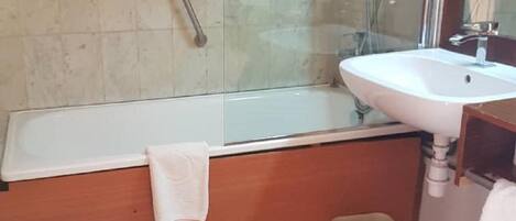 A bathroom with a bathtub, a sink, a mirror, and a glass shower enclosure.