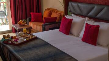 A hotel room with a bed, a breakfast tray, a chair, and a window with curtains.