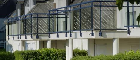 Un bâtiment moderne à la façade blanche, agrémenté de balustrades bleues et d’une série de fenêtres.