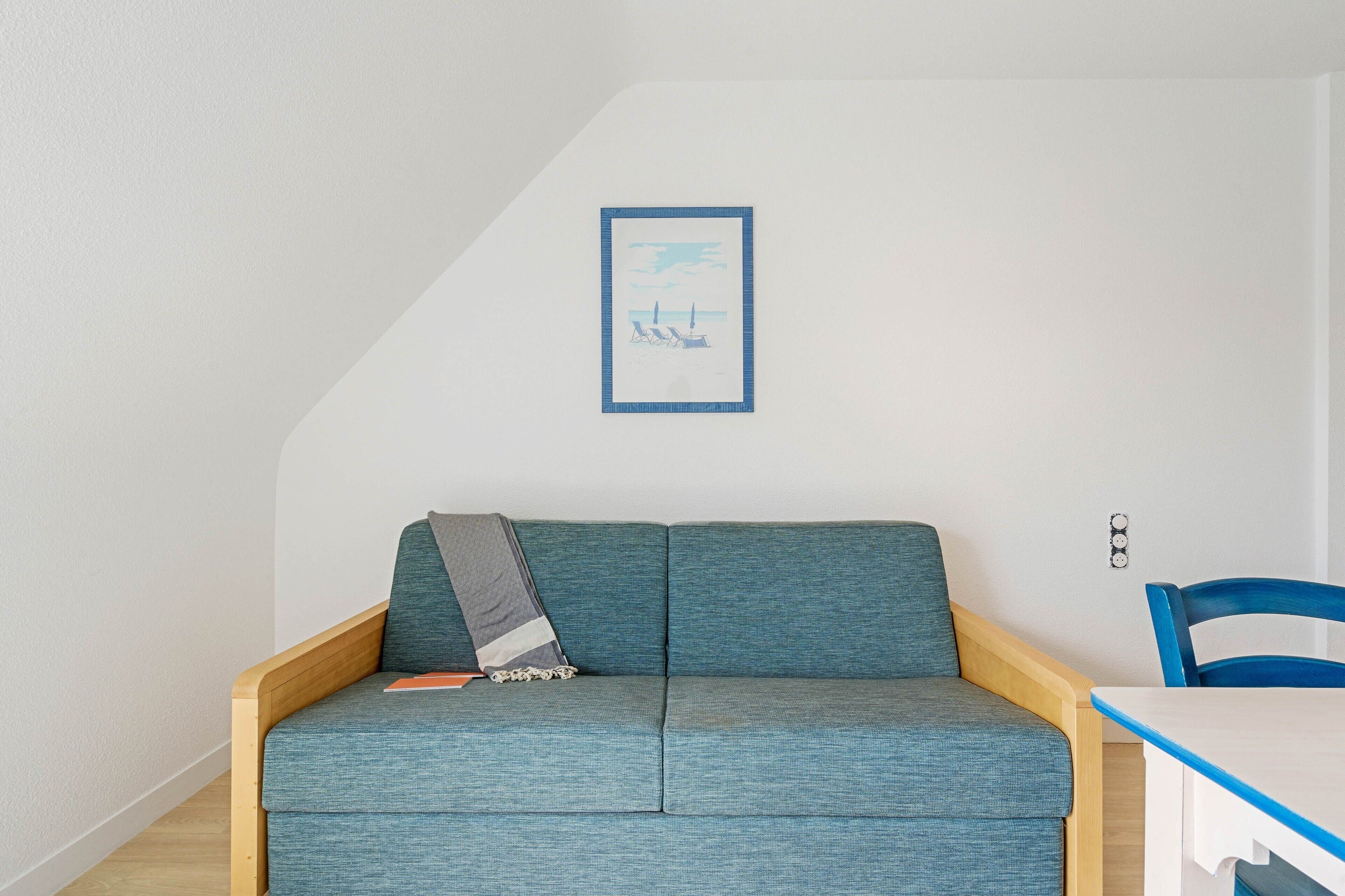 Una habitación con un sofá azul, una mesita y un cuadro en la pared.