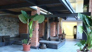 A covered outdoor area with brick walls, large potted plants, and a stone wall. - Il Vecchio Mulino di Bairo (Bairo)
