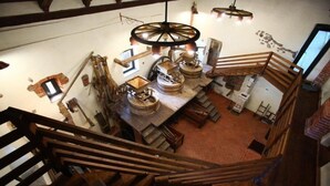 A multi-level wooden interior with exposed beams, a central wooden table, and a ceiling fan. - Il Vecchio Mulino di Bairo (Bairo)