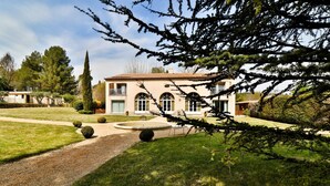 A two-story house with a garden, a driveway, and a circular fountain. - Maison d'Hôtes de la Milane (Cabries)