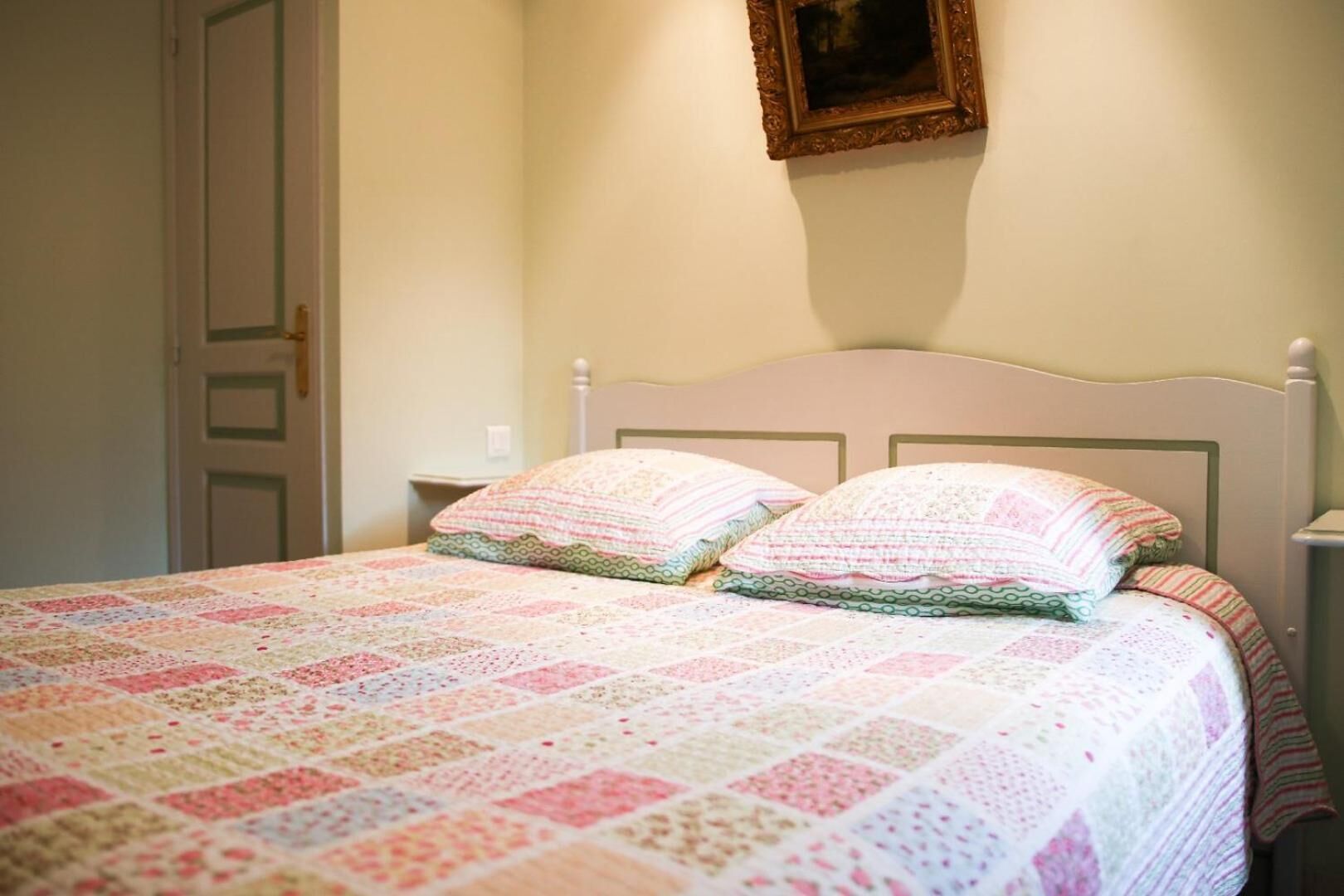 Un dormitorio con una cama, almohadas y una mesita de noche.