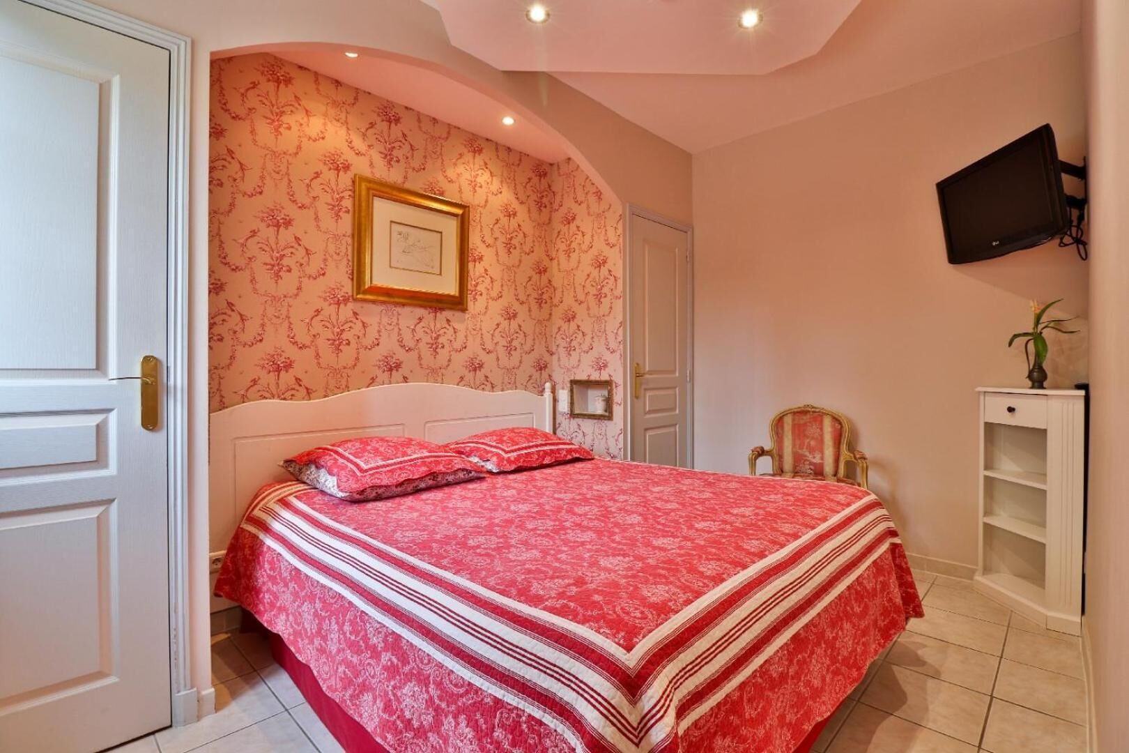 Un dormitorio con cama, televisión y puerta.