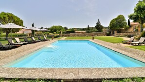 A rectangular swimming pool with clear blue water, surrounded by a stone deck. There are lounge chairs and umbrellas along the poolside. - Maison d'Hôtes de la Milane (Cabries)