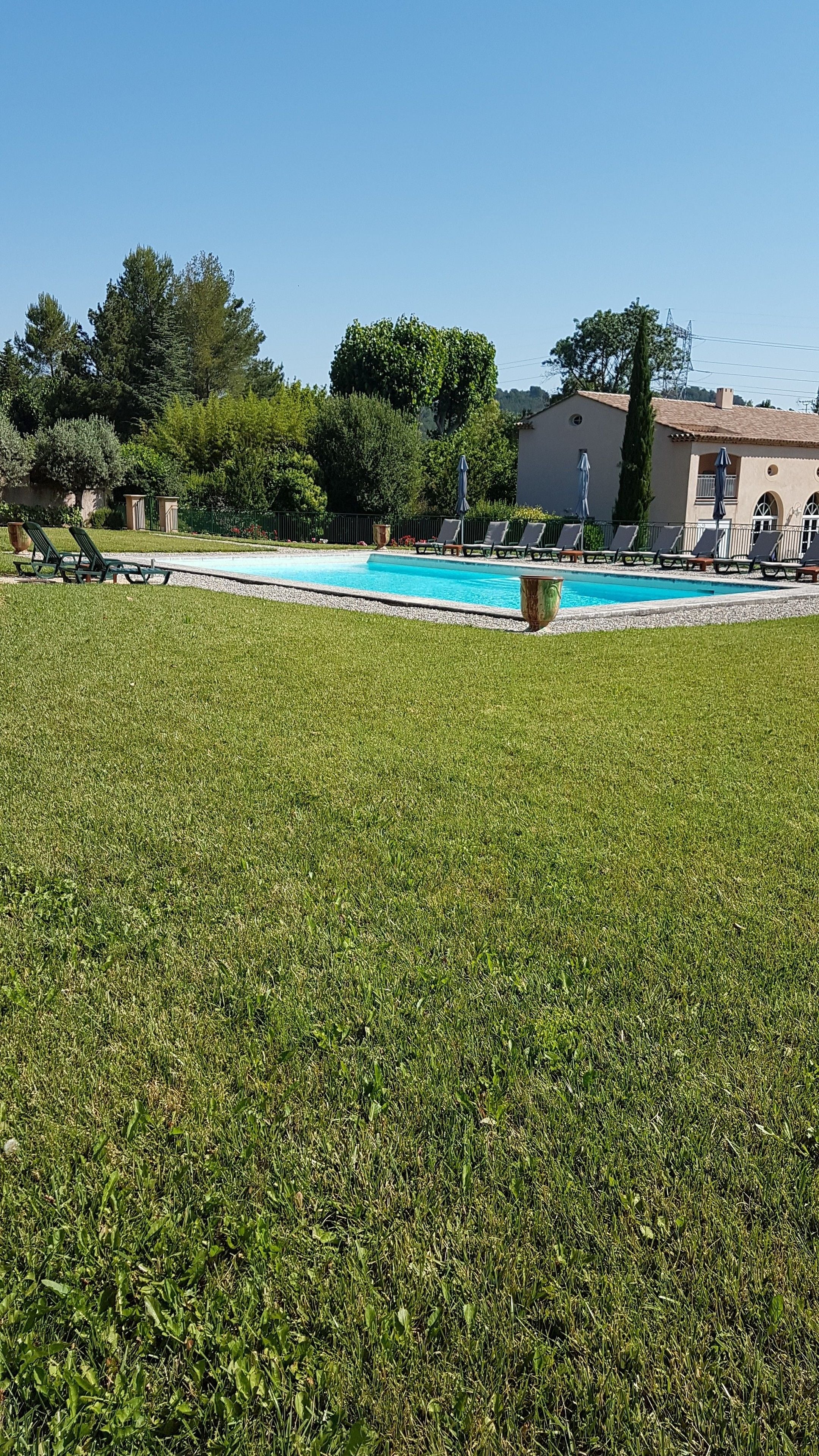Una piscina con sillas de descanso y un edificio al fondo.