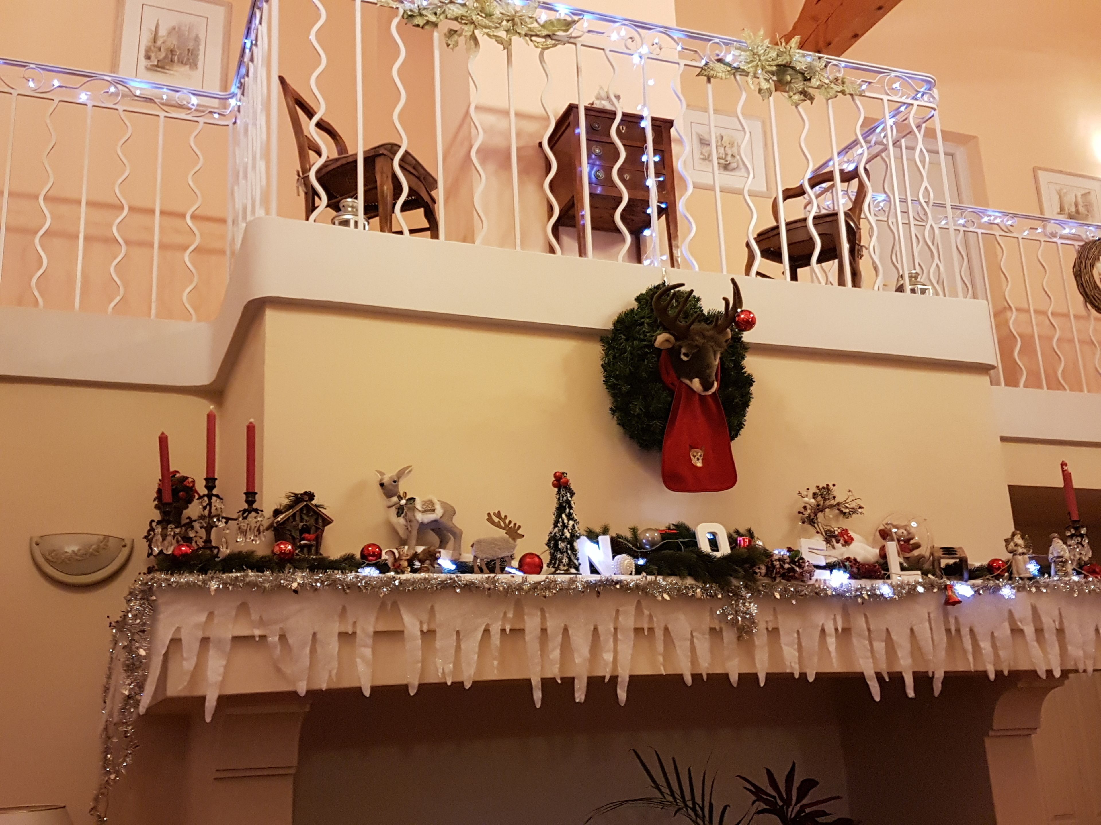 Una repisa de chimenea decorada con adornos navideños, un adorno y un calcetín rojo.