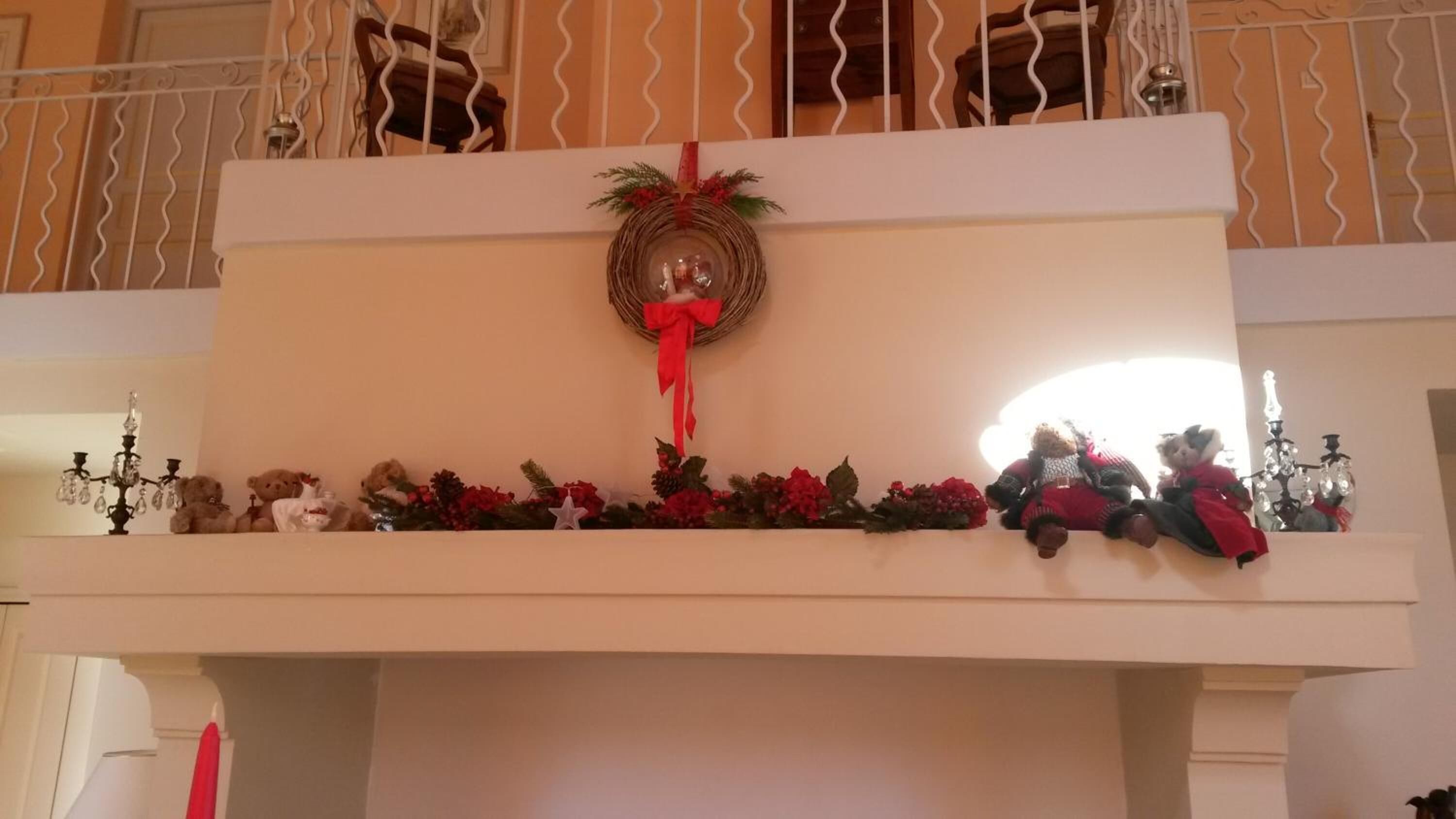 A decorated balcony with a wreath, Christmas decorations, and a chandelier.