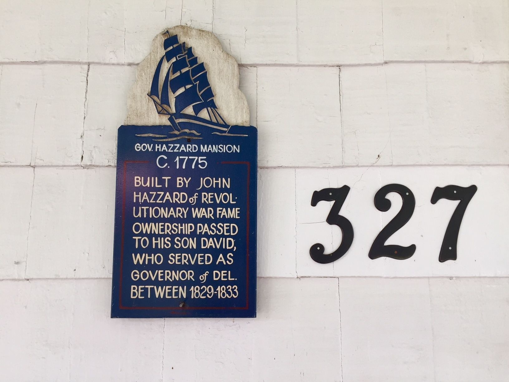 A historical plaque on a white wall with the number 327.